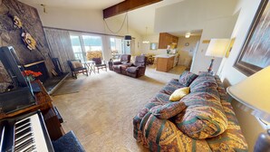 Uma sala de estar ampla com sofá, cadeiras, piano e lareira.