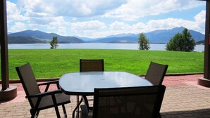 Une table et des chaises sur une terrasse offrant une vue sur un lac et des montagnes.