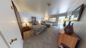 Two double beds with matching bedding, a bedside table, and a dresser with mirror and vases.