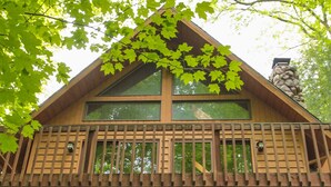 Une cabane en bois dotée d’un balcon, entourée d’arbres.