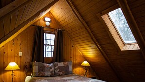 Une chambre confortable située dans les combles, avec un grand lit, deux lampes de chevet et une lucarne.