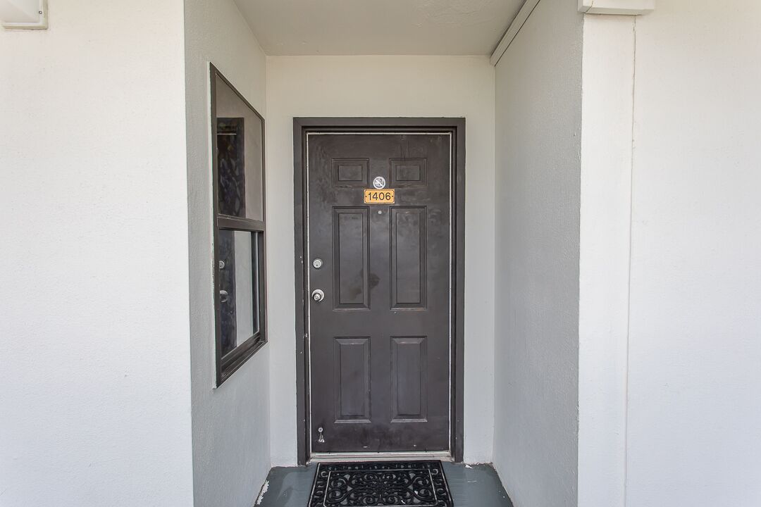 A dark brown door with a number plate reading "1406" and a small window to the left.