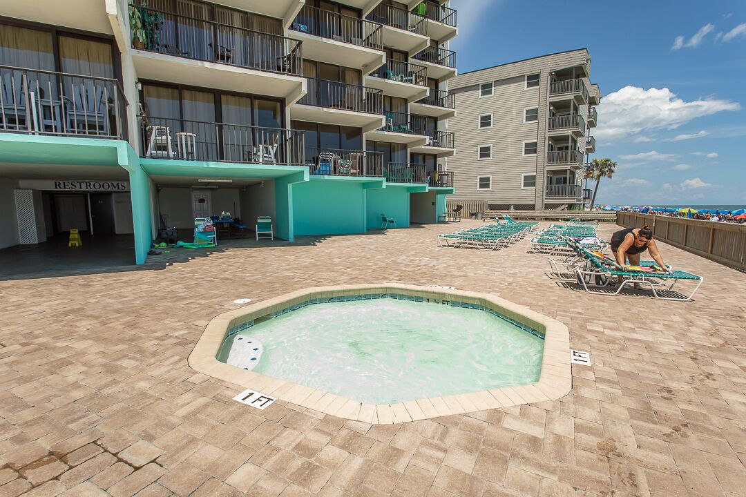 A pool area with lounge chairs and a sign indicating a 1.5 ft depth.