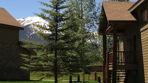 A lodge with a stone facade, wooden deck, and a view of snow-capped mountains. - Private Hot Tub, Lift Chairs. On River Rec Trail. Easy Drive to Dine, Shop (Silverthorne)