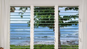 Una habitación con vista al océano a través de una ventana con persianas horizontales.