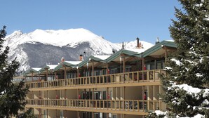A multi-story hotel with balconies, snow-covered surroundings, and a mountain in the background. - On Lake, Views! Hot Tub. Walk to Concerts, Marina, Dining. 1st Floor (Dillon)