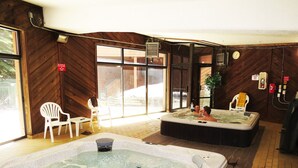 Een wellnessruimte met twee bubbelbaden, houten wanden en een groot raam.