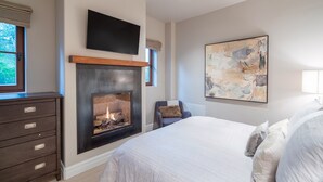 Une chambre à coucher avec une cheminée, un lit, une commode et un tableau au mur.