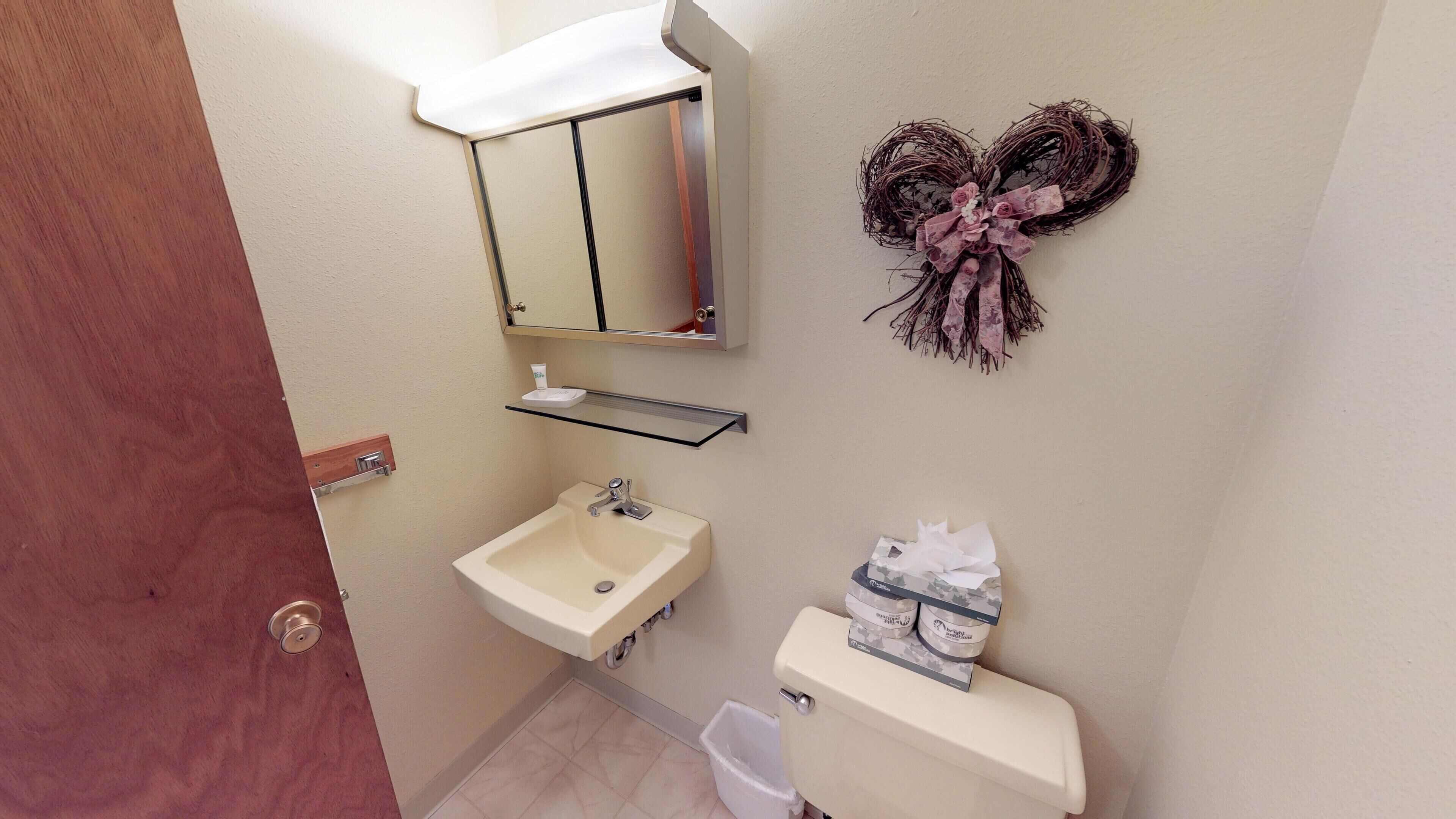 Un baño pequeño con lavamanos, espejo e inodoro.