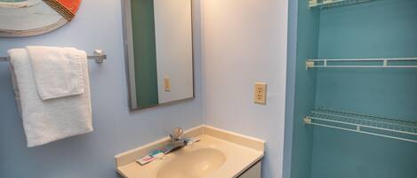 A bathroom with a sink, mirror, and towel rack.