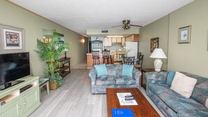 A living room with a television, sofa, coffee table, and a dining area in the background. - Beachfront comfort with unforgettable views (Murrells Inlet)