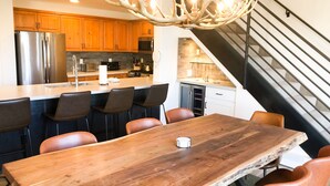 Une cuisine moderne avec des meubles en bois, des appareils en acier inoxydable et un îlot central doté de tabourets de bar.