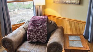 A cozy room with a leather armchair, a small wooden table, and a painting on the wall.