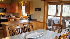A modern kitchen with wooden cabinets, a central island, and a dining area with a large table and chairs.