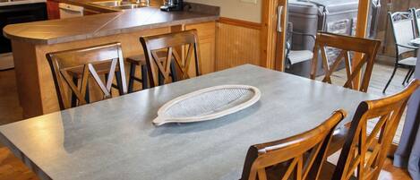 Una cocina moderna con armarios de madera, una isla central y un comedor con una mesa grande y sillas.
