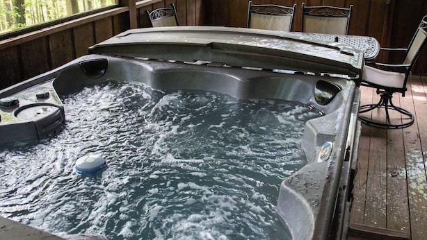 A hot tub with water, surrounded by wooden walls and chairs.