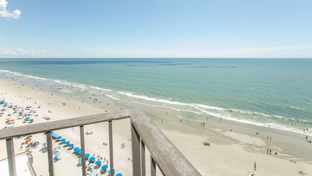A beach with umbrellas and people. - 14th-floor oceanfront condo with breathtaking views (Murrells Inlet)