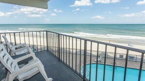 Uma varanda com vista para a praia e uma piscina.