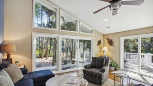 A spacious living room with a large window, a ceiling fan, and a comfortable seating area.
