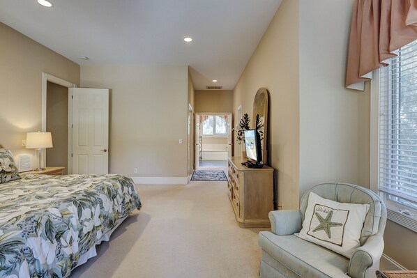 A bedroom with a bed, dresser, mirror, and a chair with a starfish pillow.