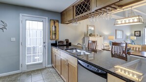 Una cocina con armarios de madera, lavavajillas integrado, encimera con un tostador y ventana con persianas.