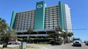 A multi-story hotel with a prominent "Royal Garden" sign, a parking garage, and palm trees. - LARGE AND LOVELY! LOTS OF ROOM IN THIS 3 BEDROOM CONDO RIGHT ON THE OCEAN! (Murrells Inlet)