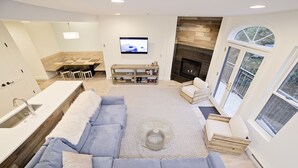 A modern living room with a large gray sectional sofa, a fireplace, and a dining area with a wooden table and chairs.
