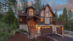 A two-story log cabin with a stone foundation, a front porch, and a garage.