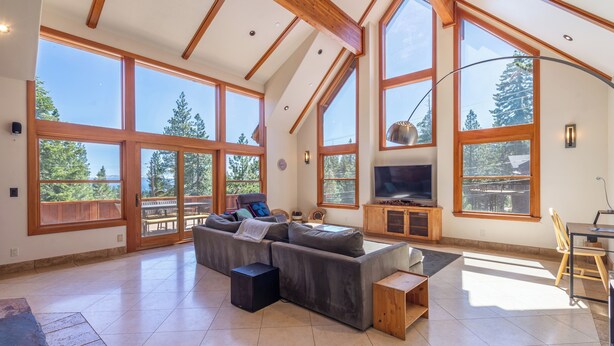 A spacious living room with a large sectional sofa, a flat-screen TV, and a dining area with a wooden table and chairs.