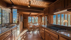 A spacious kitchen with wooden cabinets, a central island, and large windows offering a view of the outdoors. - View at Dollar Point by Tahoe Getaways -  Lake Views in Tahoe City (Tahoe City)