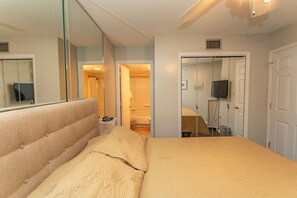 Een slaapkamer met een groot bed, een spiegel en een deur naar een badkamer.
