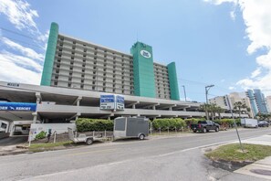 A hotel with a green and white facade, a parking garage, and a sign for the Royal Garden Hotel. - Beachfront Relaxation Starts Here (Murrells Inlet)