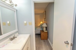 A bathroom with a double sink, a mirror, and a bedside table with a lamp. - Beachfront Relaxation Starts Here (Murrells Inlet)