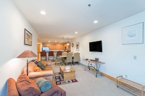 Relax in a comfortable seating area with a sofa and ottoman, surrounded by a patterned rug and a wooden coffee table.
