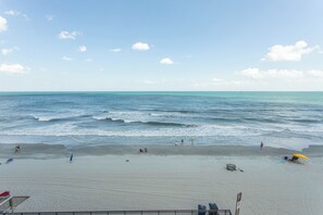 A beach with a sandy shore, a few umbrellas, and a clear sky. - OCEANFRONT LARGE 2 BEDROOM CONDO (Murrells Inlet)