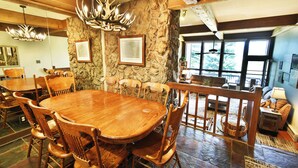 A rustic dining area with a large wooden table and chairs, stone walls, and a stone fireplace. - Near Lake Dillon! 3 Kings. Hot Tub, Yard. On Rec Path, Near Dining, Shops (Keystone)