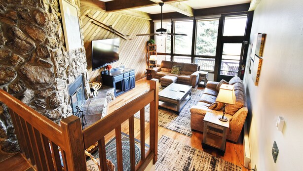 A cozy living room with a stone wall, wooden beams, a fireplace, a flat-screen TV, a sofa, and a coffee table. - Near Lake Dillon! 3 Kings. Hot Tub, Yard. On Rec Path, Near Dining, Shops (Keystone)