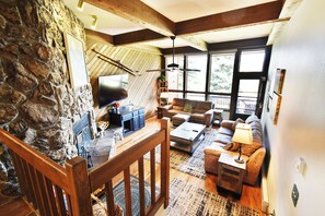A cozy living room with a stone wall, wooden beams, a fireplace, a flat-screen TV, a sofa, and a coffee table. - Near Lake Dillon! 3 Kings. Hot Tub, Yard. On Rec Path, Near Dining, Shops (Keystone)