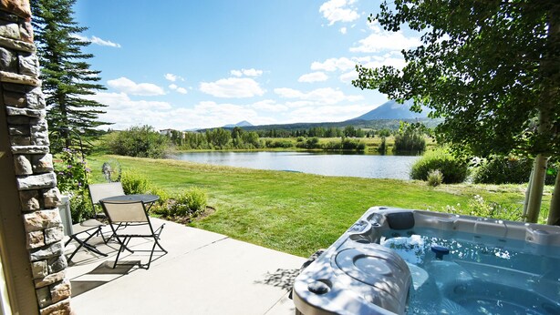 Ein Whirlpool auf einer Terrasse mit Blick auf einen See und Berge.