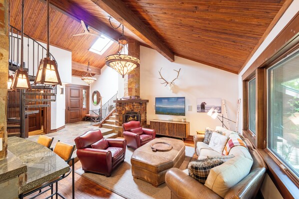 A spacious living area with a fireplace, leather furniture, and a large window.