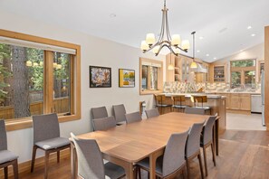Enjoy meals in this spacious dining area with a large table and comfortable seating for six, offering a forest view.