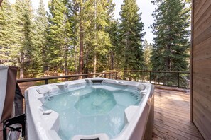 Relax in a serene hot tub surrounded by a dense forest of evergreen trees.