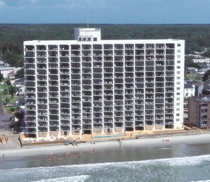 Un grand hôtel doté de nombreux balcons, d’un espace piscine et offrant une vue sur la plage.