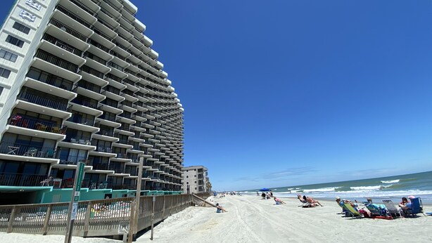 A high-rise hotel with multiple balconies, a sandy beach in the foreground, and the ocean in the background. - COZY LITTLE 1 BEDROOM CONDO (Murrells Inlet)