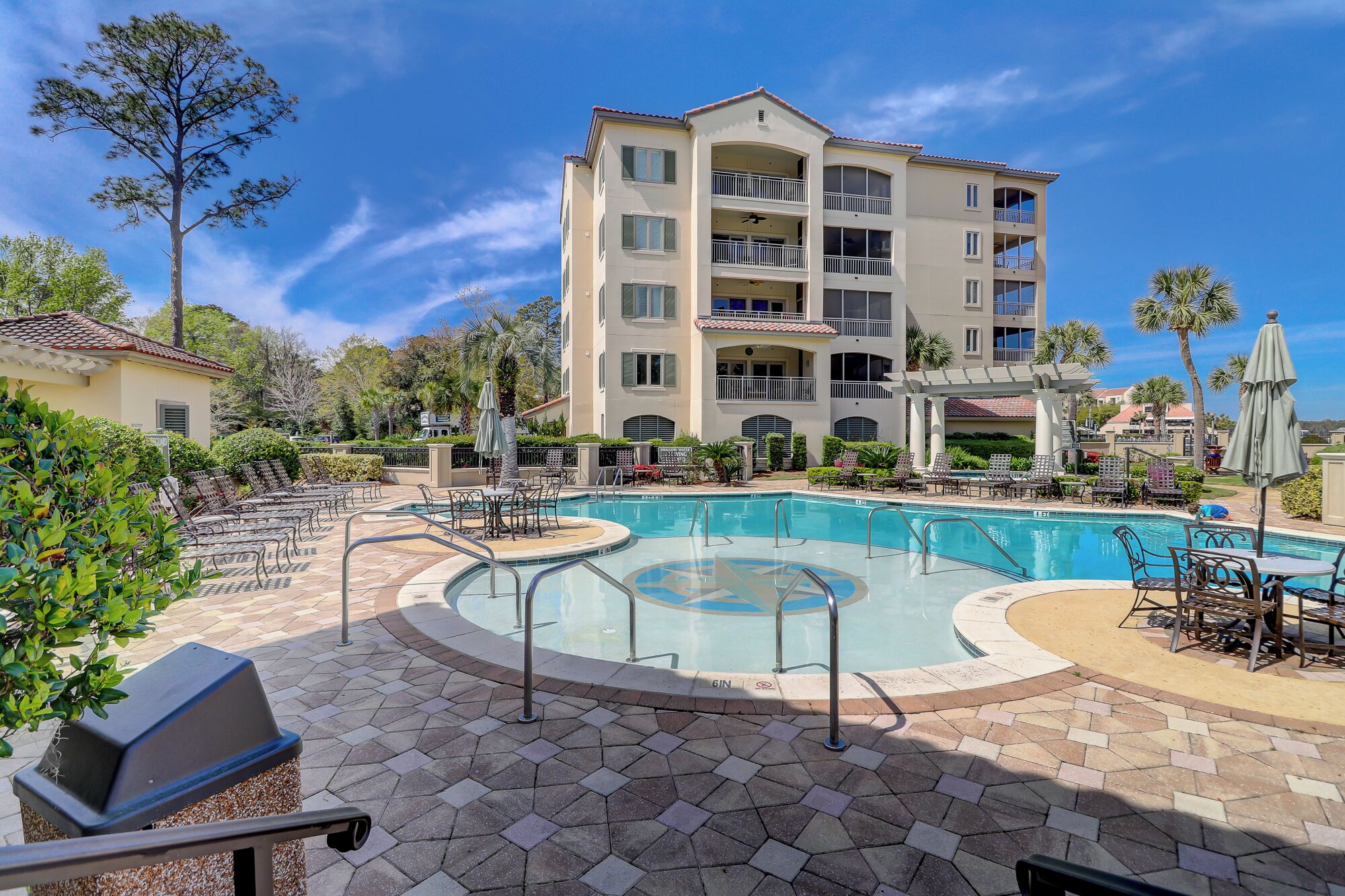 A hotel with a large outdoor pool, multiple balconies, and outdoor seating areas.