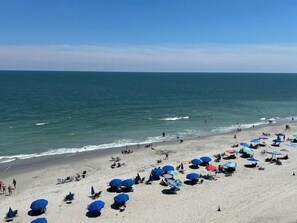 A beach with numerous umbrellas and people.