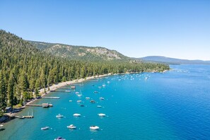 Una zona costera con un puerto deportivo, barcos y un promontorio cubierto de bosque.