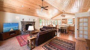 A spacious living room with a fireplace, leather sofa, and a television.