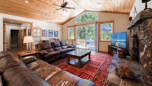 A spacious living room with a leather sofa, a coffee table, and a stone fireplace.