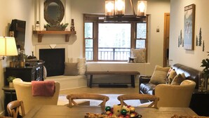 Un salon confortable avec une cheminée, un téléviseur et une grande fenêtre.
